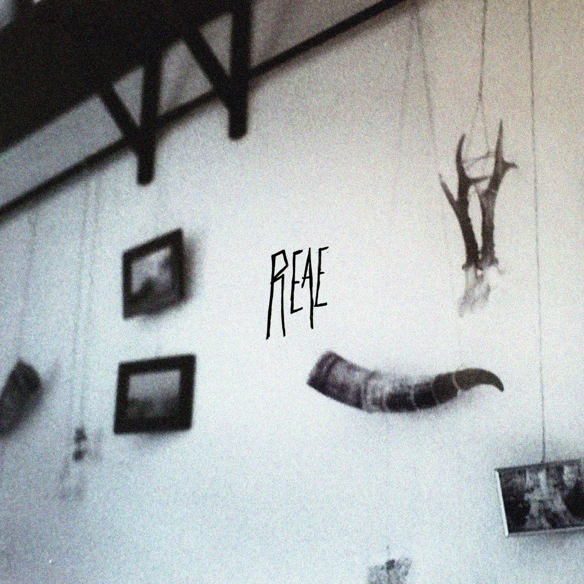 Cover for the track '[sf] Prehend the Room #0 - Pièce de vie' by REAE. Granulated black and white photograph of a living room wall with photographs and animal horns hanging on threads.